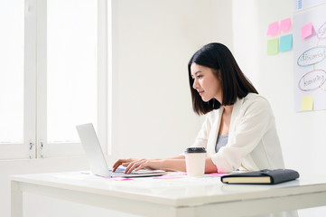 Concept of work from home. Young asian business woman working on computer laptop in office room with paperwork document on desk