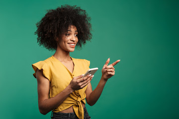 Photo of african american woman pointing finger and using cellphone