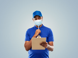 Fototapeta na wymiar health, safety and pandemic concept - happy indian delivery man wearing face protective medical mask for protection from virus disease with clipboard in blue uniform over grey background