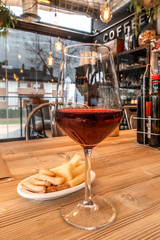 A glass of wine, cheese, and breadsticks in a bar