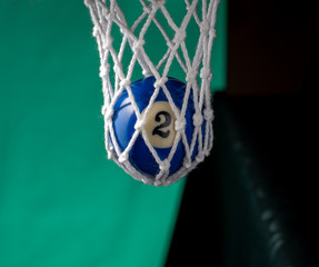 In billiard pocket a ball no. two on a green backgound.