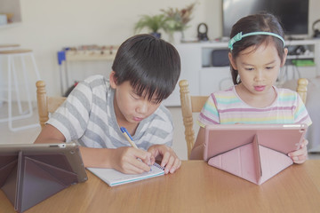mixed Asian children using digital tablet at home, listening to podcast, gaming, online learning education, elearning, homeschooling, social distancing, isolation,new normal concept