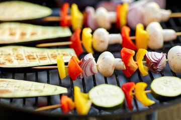 cooking, barbecue and food concept - close up of eggplant slices and vegetables with champignon...