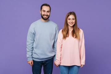 Fototapeta premium Positive loving couple isolated over purple background.