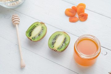 Kiwi, honey and dried apricots lie on a white wooden table. Healthy breakfast.