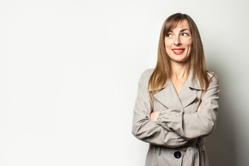 Portrait of a young friendly woman in a classic jacket looks away on an isolated light background. Emotional face