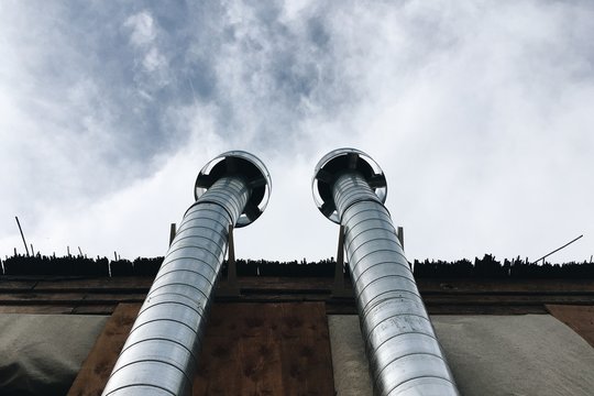 Low Angle View Of Factory Pipes Against Cloudy Sky