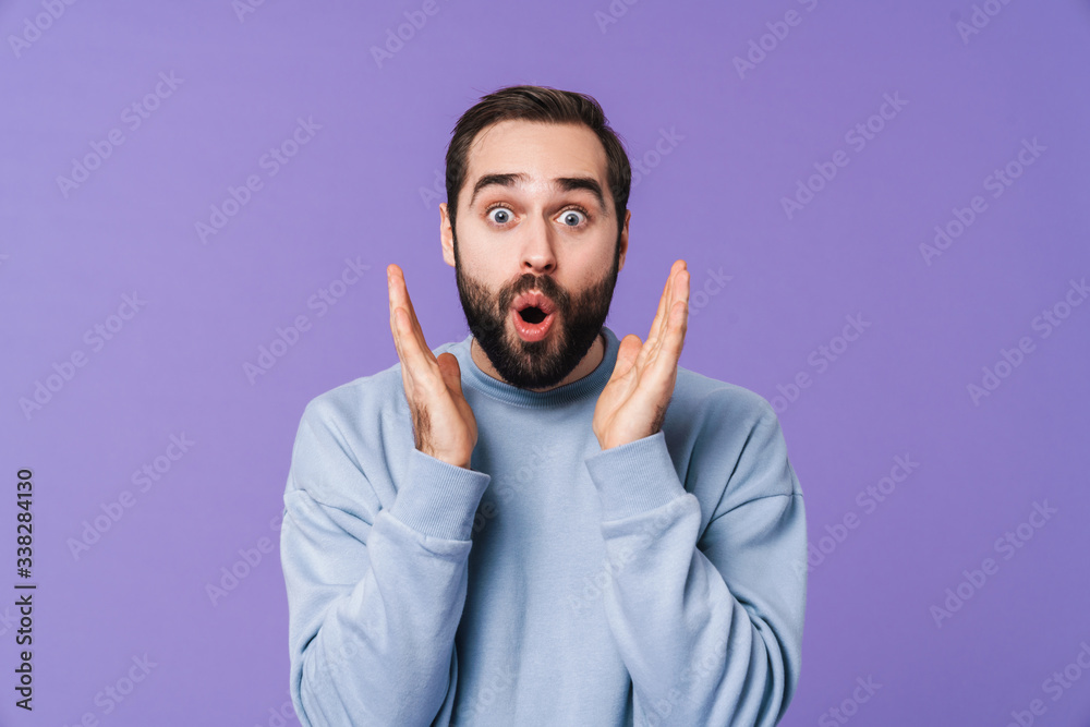 Wall mural Surprised handsome young man over purple background.