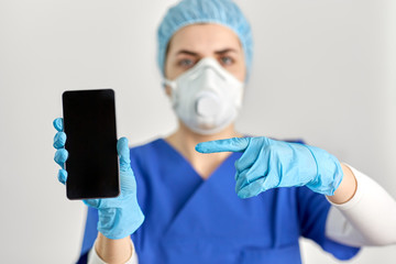 Fototapeta na wymiar medicine, health and pandemic concept - close up of young female doctor or nurse wearing face protective mask or respirator for protection from virus disease with smartphone