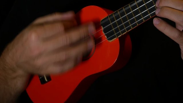 musician is playing some chords on an orange ukulele