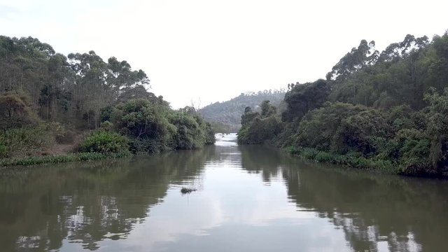 Slow fly over River going to resevoir, surrounded by tree foliage