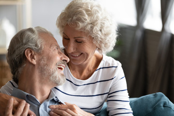 Happy older woman and man having fun close up, laughing aged wife and husband looking at each other, mature family enjoying tender moment, senior spouses spending free time together at home