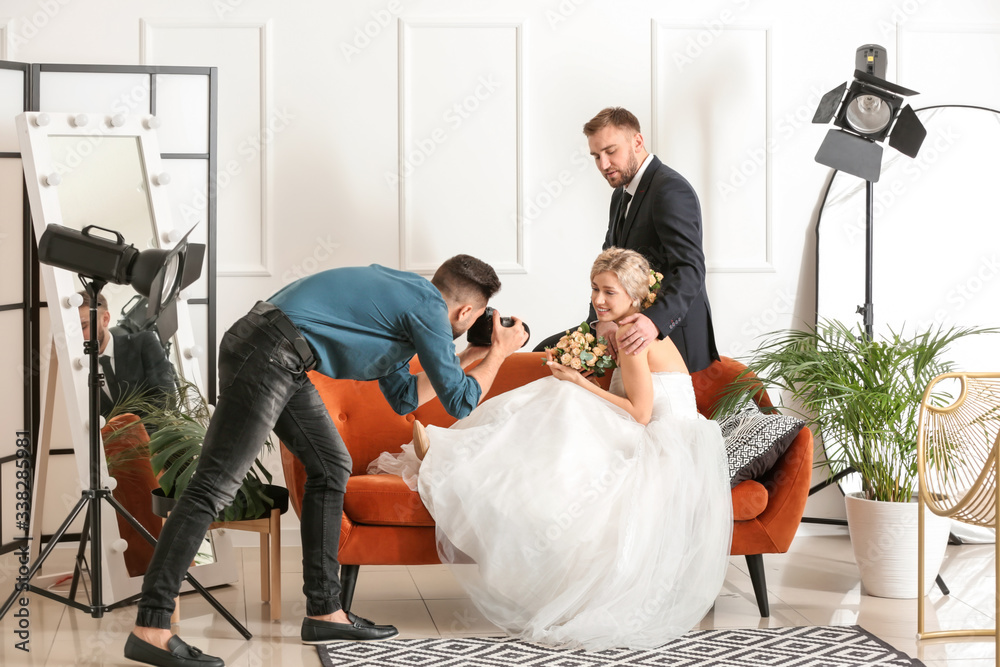 Wall mural Photographer working with young wedding couple in studio