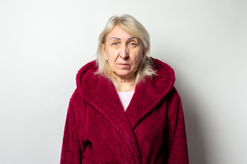 Portrait of an old friendly woman in a casual coat on an isolated light background. Emotional face