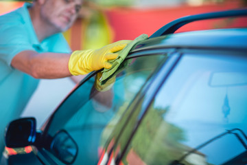 Man holding the microfiber in hand and polishes the car.