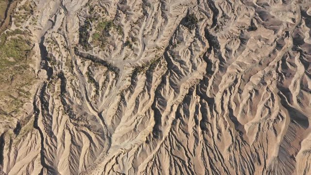 Drone bird's eye view of Sea of Sand desert to tilt reveal of town, Bromo volcano National Park.