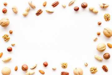 Fototapeta na wymiar Nuts background - healthy snacks concept - on white table top-down frame copy space