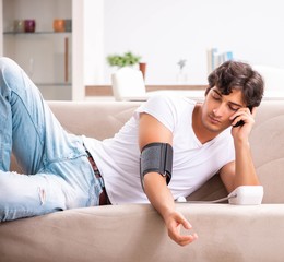 Young man measuring blood pressure at home