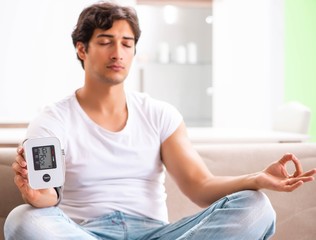 Young man measuring blood pressure at home