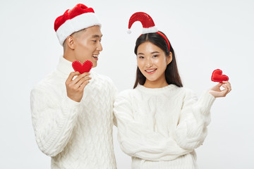 young couple in santa hats holding christmas balls
