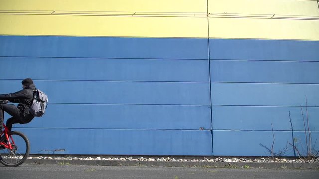 Cool young man wheelies with Mountainbike MTB Bike next to colorful wall / Slowmo / Outdoor Action & Fun Sports