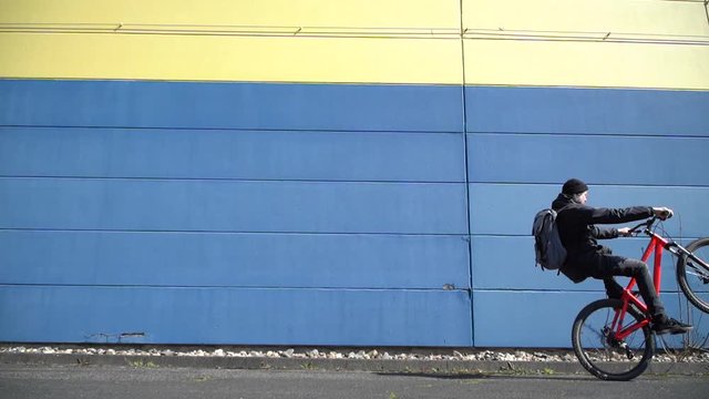 Cool man wheelies with Mountainbike MTB Bike next to colorful wall / Slowmo / Outdoor Action & Fun Sports