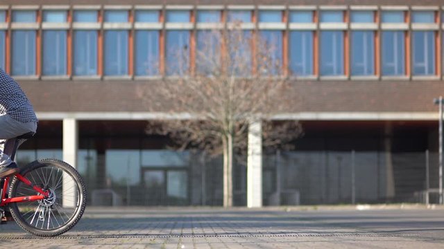 Cool athlete wheelies with Mountainbike MTB Bike next urban building / Outdoor Action & Fun Sports