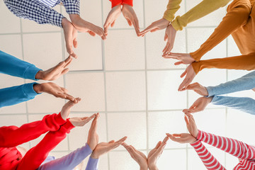 Group of people putting hands together indoors, bottom view. Unity concept