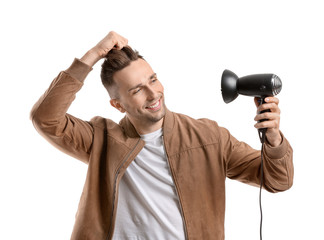 Handsome young man with hair dryer on white background