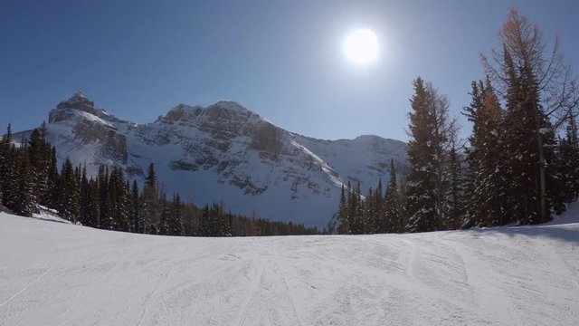 Slow motion skiing view of a mountain and sun with clear skies