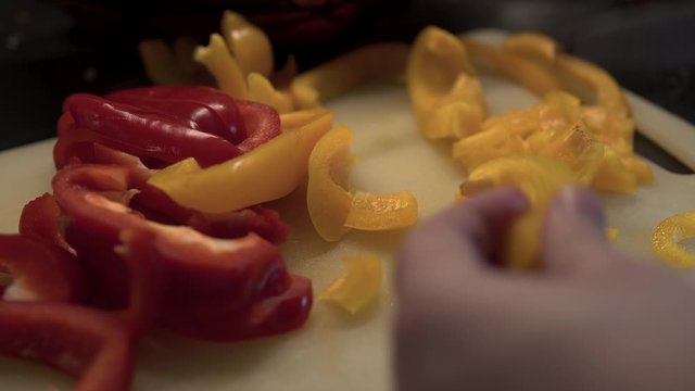 Slicing colour pappers, the hand covers the knife blade and the cut part of the vegetable
