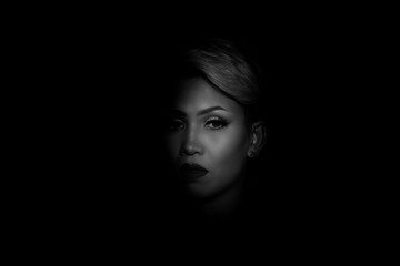 Portait photography of the face of a young asian woman with black background. Spot light portrait. Expressive girl portrait on dark background. Girl with a spot of light on her face. Sad face.