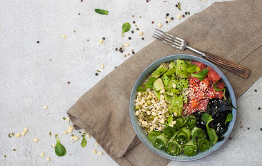 Poke bowl with smoked salmon, cucumber, avocado, sea kale, bean sprouts, sesame and herbs. Grey background, copy space.