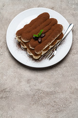 Classic tiramisu dessert on ceramic plate on light grey concrete background