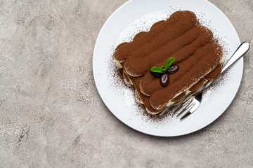 Classic tiramisu dessert on ceramic plate on light grey concrete background
