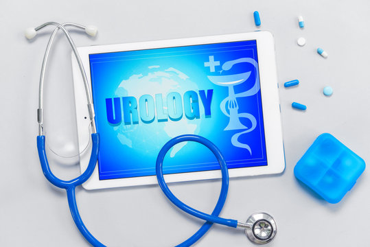 Tablet computer with text UROLOGY, medicines and stethoscope on grey background
