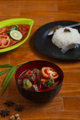 indonesian beef stew on a black bowl over wooden background. traditional meat soup.
