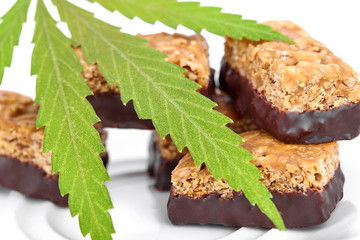 Candy with the addition of medical cannabis CBD for recreational use to relax body and mind. Sweet cannabis candy CBD Cannabidiol next to green leaves of marijuana on white isolated background