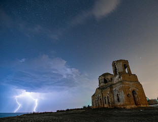 Naklejka na ściany i meble Lighting at Night starry sky near destroyed abandoned Cathedral, HDR