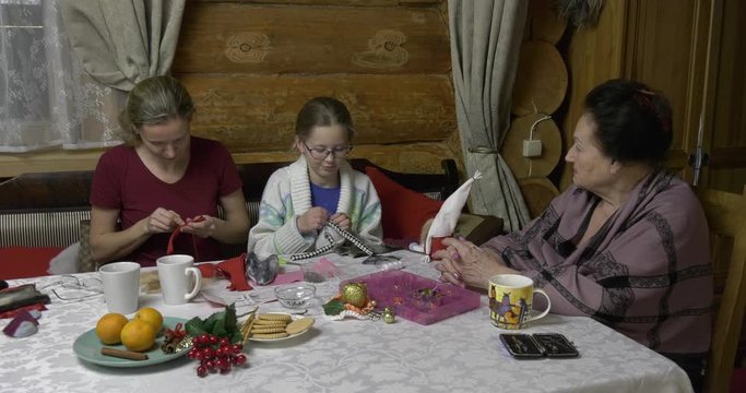 Daughter, mother and grandmother make toys at the table for the New Year holiday. Family evening in the run-up to the holiday three generations of craftswomen make soft toys with their own hands.