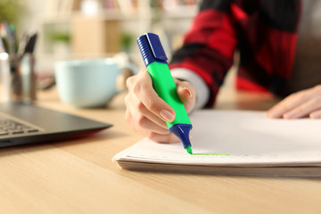 Student girl hands using highlighter pen on notebook