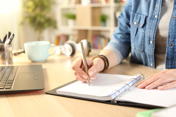 Student girl hand writing on notebook at home