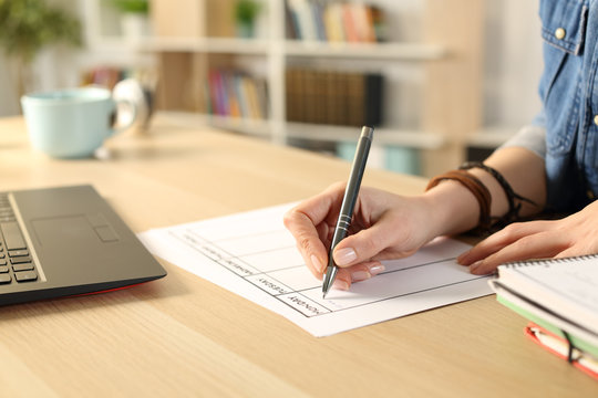 Student hand writing schedule on planner at home