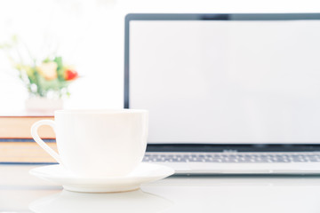 Cup of coffee with blank screen laptop computer on deck