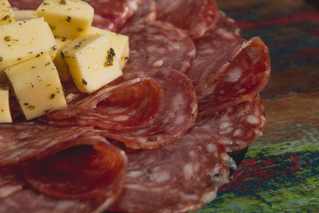 Comida de boteco brasileira linguiça calabresa fatiada fina com queijo em cubos servido em tigela em balcão de boteco