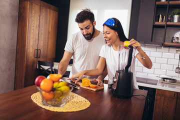 Fototapeta na wymiar Couple making fresh organic juice in kitchen together