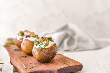 Obraz na płótnie Canvas Tasty baked potato with sour cream and mushrooms on board