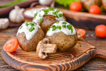 Tasty baked potato with sour cream and mushrooms on table