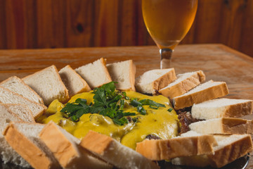 Comida de boteco brasileira picadinho de carne flié ao molho servido com pão em tigela em balcão...