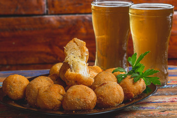 Comida de boteco brasileira salgados diversos servidos em tigelas em balcão de boteco: pastel, bolinha de queijo, coxinha e quibe